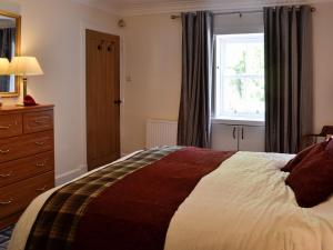 Un dormitorio con una cama grande y una ventana en Belstane Cottage, en Straiton