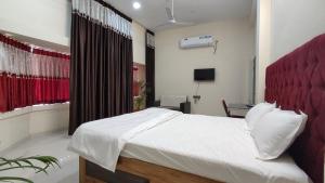 - une chambre avec un lit blanc et une tête de lit rouge dans l'établissement Anand Vihar, à Jamshedpur