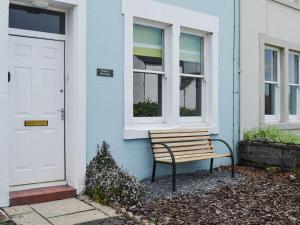 un banco de madera sentado fuera de una casa azul en Poets Retreat, en Cockermouth