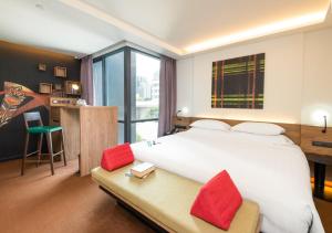 a bedroom with a large white bed with red pillows at Maitria Mode Sukhumvit 15 Bangkok - A Chatrium Collection in Bangkok