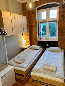 two beds in a room with a window at Apartament Odrzanka in Gryfino