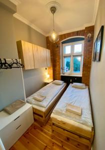 two beds in a small room with a window at Apartament Odrzanka in Gryfino