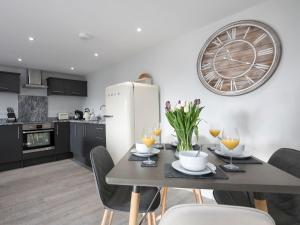 a kitchen with a table and a clock on the wall at The Cowshed in Heveningham