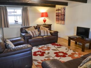 a living room with a leather couch and a television at Granary Cottage - Uk10994 in Eshott