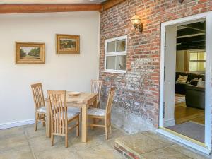 a table and chairs in a room with a brick wall at Granary Cottage - Uk10994 in Eshott