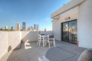 een patio met een tafel en stoelen op een balkon bij LUXURY PENTHOUSE GREAT LOCATION WITH PARKING Tlv in Ramat Gan