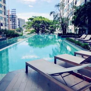 a swimming pool with a table and lounge chairs at THE BASE holiday in in Pattaya Central