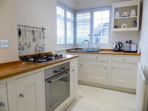 a kitchen with white cabinets and a stove top oven at Chareside Cottage in Corbridge