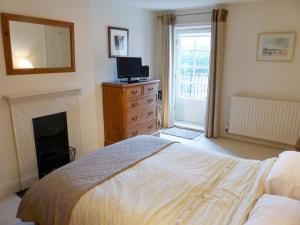 a bedroom with a bed and a fireplace and a television at Chareside Cottage in Corbridge