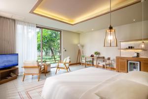 a bedroom with a large bed and a living room at FLC Luxury Hotel Samson in Sầm Sơn