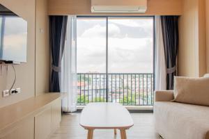 a living room with a couch and a large window at ONE Hotel in Pathum Thani