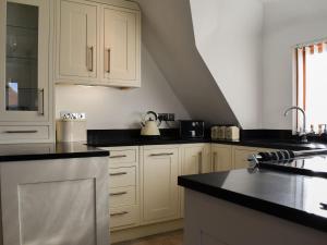 a kitchen with white cabinets and black counter tops at The Studio in Aldington