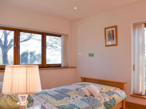 a bedroom with a bed with a lamp and windows at The Studio in Aldington