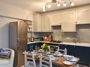 a kitchen with a table with chairs and a refrigerator at Princessa Cottage in Bembridge