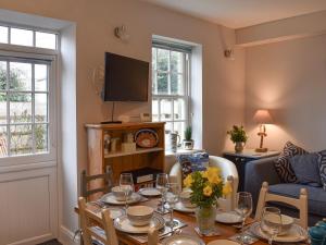 a living room with a table and a tv at Princessa Cottage in Bembridge