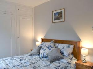 a bed with blue and white sheets and pillows at Princessa Cottage in Bembridge