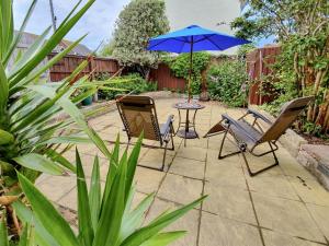 a patio with chairs and a table with an umbrella at Princessa Cottage in Bembridge