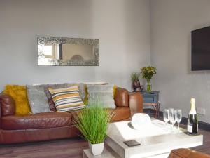 ein Wohnzimmer mit einem braunen Ledersofa und einem Tisch in der Unterkunft Reflections in Saint Monance