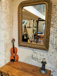 een viool op een tafel voor een spiegel bij Loft atypique au calme avec cour privative in Bourges