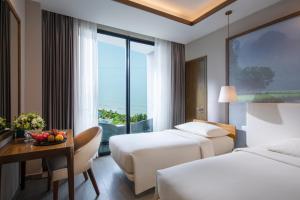 a hotel room with two beds and a table with a bowl of fruit at FLC Grand Hotel Samson in Sầm Sơn