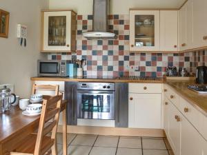 a kitchen with a stove and a table with chairs at Stanley Barn in Stonehouse