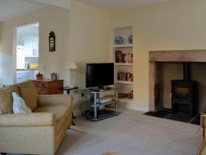 sala de estar con sofá, TV y chimenea en Dairy Cottage en Whitehouse