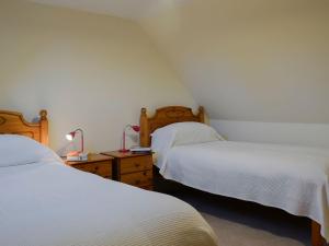 a bedroom with two beds and a table with a lamp at Dairy Cottage in Whitehouse
