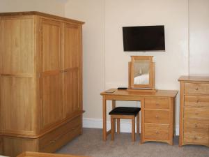 a bedroom with a dresser and a desk with a television at Squirrels Retreat - Uk30821 in Braithwaite