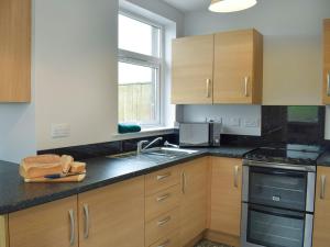 a kitchen with wooden cabinets and a black counter top at Brick Cottage 1-uk13674 in Palnure