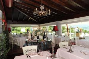 un ristorante con tavoli e sedie bianchi e un lampadario a braccio di Villa Baroni a Lomnago