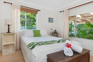 a bedroom with a white bed with a red bow on it at WategosRent in Byron Bay