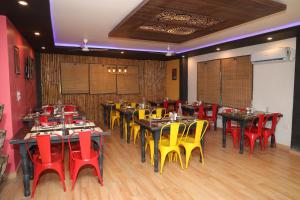 ein Restaurant mit Tischen und gelben und roten Stühlen in der Unterkunft Hotel Cordelia inn in Rishikesh