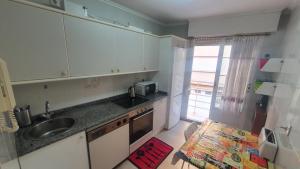 eine Küche mit weißen Schränken, einem Waschbecken und einem Fenster in der Unterkunft Tauco Ribadesella - Estupendo piso para 5 pax in Ribadesella