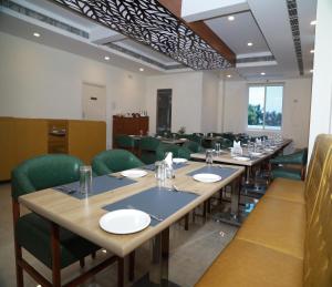 a dining room with long tables and green chairs at Hotel Royal Chola in Kanchipuram