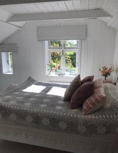 1 dormitorio con cama con almohadas y ventana en Småbruket stall solheim, en Rødby