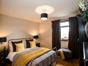 a bedroom with a bed with yellow pillows and a window at Woodend in Maxwelltown