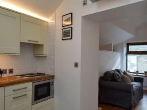 uma cozinha com armários brancos e um sofá num quarto em Kinder Apartment - Uk12957 em Glossop