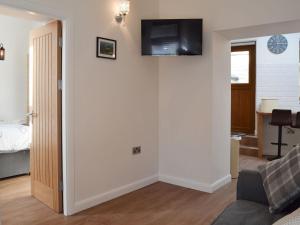 a living room with a couch and a television on a wall at Kinder Apartment - Uk12957 in Glossop