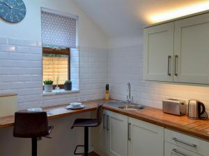 a kitchen with a sink and a counter with two chairs at Kinder Apartment - Uk12957 in Glossop