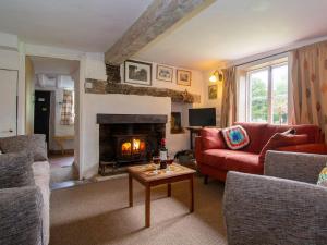 a living room with a red couch and a fireplace at Avebury Cottage in Avebury