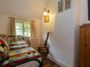 um quarto com uma cama, uma cadeira e uma janela em Avebury Cottage em Avebury