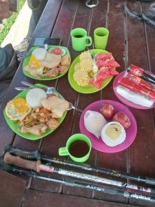 a table with plates of food and cups of coffee at Bukit Senaru Homestay in Senaru