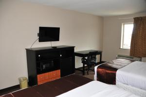 Habitación de hotel con cama, TV y escritorio. en Paradise Inn & Suites en Baton Rouge