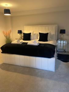 a large white bed with black and white pillows at The Bay house Apartments , shanklin in Shanklin