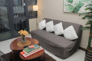 ein Wohnzimmer mit einem Sofa mit Kissen und einem Tisch in der Unterkunft A2J Luxury 1BR Suite Near Venice Mall BGC Taguig in Manila