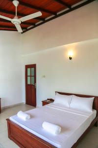 a bedroom with a bed with white sheets and a ceiling at Cinnamon Fence in Colombo