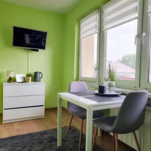 jadalnia z zielonymi ścianami oraz białym stołem i krzesłami w obiekcie Fredry 15F w Krakowie