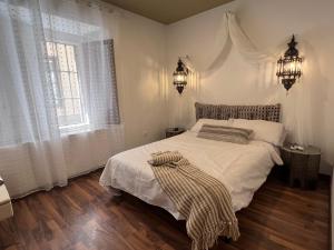 a bedroom with a bed with white sheets and a window at Sueños de la Alhambra in Granada