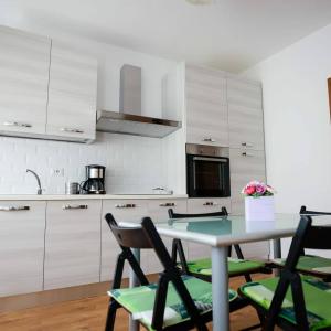 a kitchen with white cabinets and a table with chairs at Green House Alba Iulia in Alba Iulia