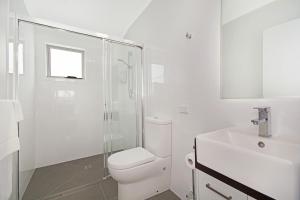 a white bathroom with a toilet and a sink at Cooroy Luxury Motel Apartments in Cooroy +19 photos
